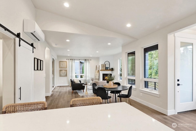 dining area with hardwood / wood-style floors, plenty of natural light, a barn door, and an AC wall unit