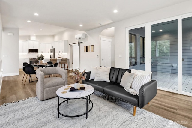 living room featuring a barn door, light wood-type flooring, and an AC wall unit