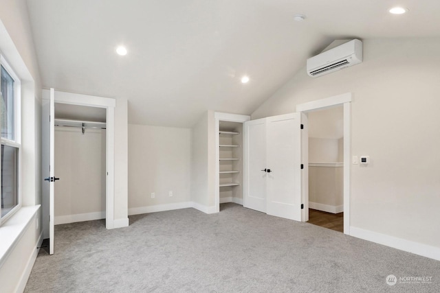 unfurnished bedroom featuring carpet flooring, a wall mounted AC, and lofted ceiling