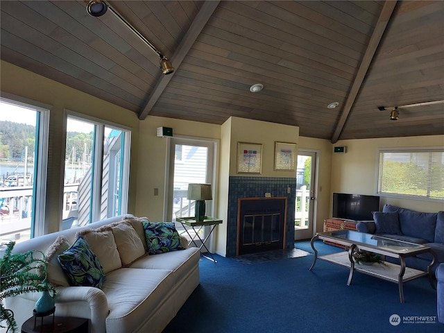 carpeted living room with a fireplace, vaulted ceiling with beams, rail lighting, and wood ceiling