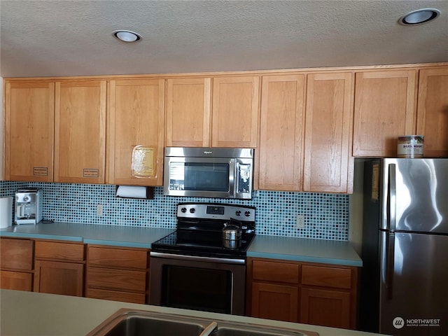 kitchen featuring backsplash, a textured ceiling, and appliances with stainless steel finishes