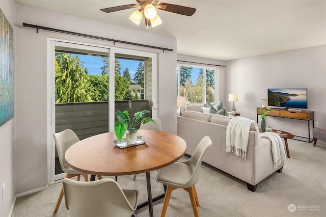 dining area with ceiling fan and light colored carpet