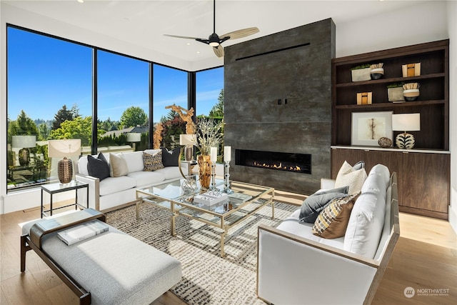 living room with ceiling fan, a fireplace, and light hardwood / wood-style floors