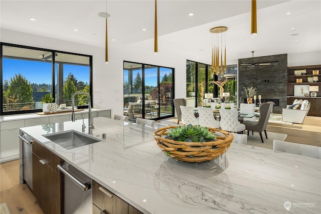 kitchen featuring a wealth of natural light, light stone countertops, sink, and hanging light fixtures