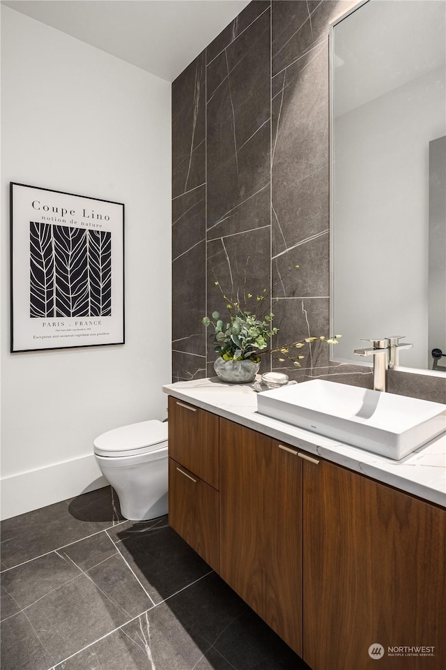 bathroom with vanity, toilet, and tile walls