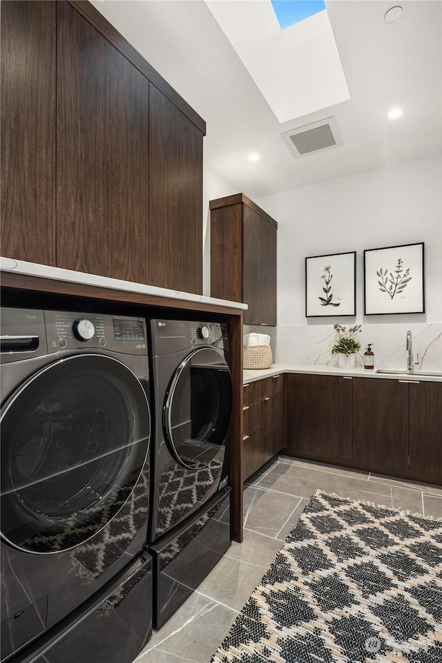 laundry area with a skylight, washer and clothes dryer, cabinets, and sink