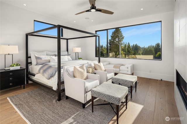 bedroom featuring ceiling fan, multiple windows, and light hardwood / wood-style flooring