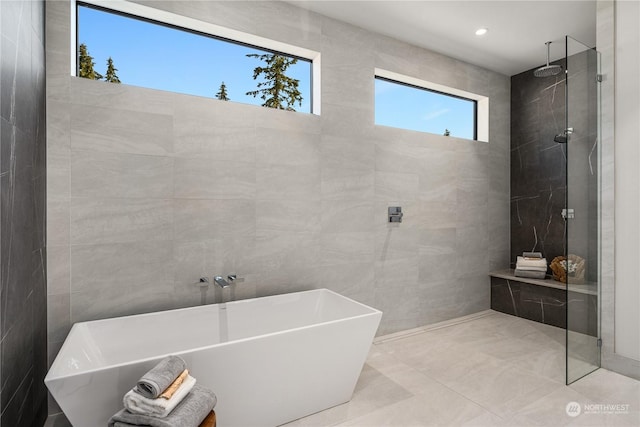 bathroom featuring plus walk in shower and tile walls