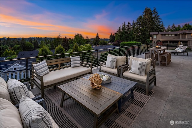 patio terrace at dusk featuring outdoor lounge area and a balcony