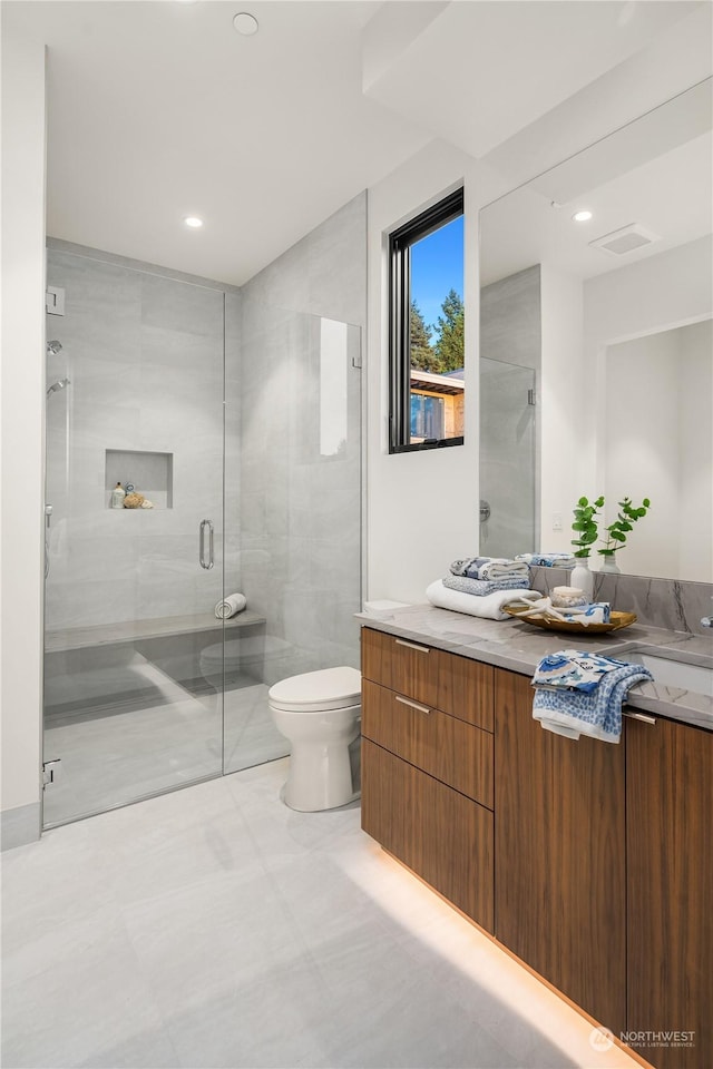 bathroom with vanity, a shower with shower door, and toilet