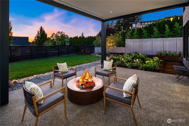 patio terrace at dusk featuring a yard and an outdoor fire pit