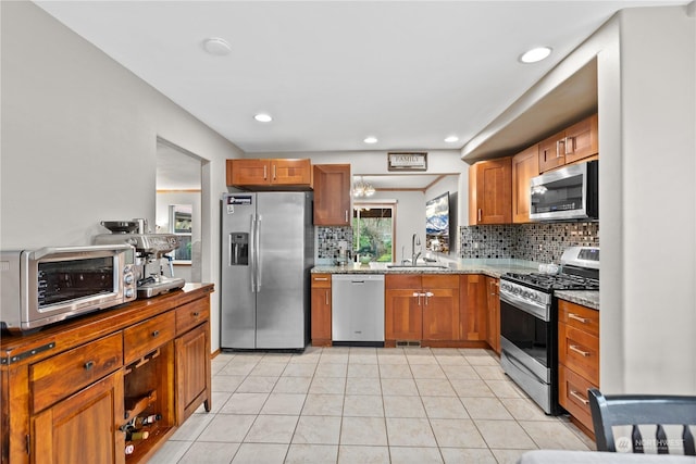 kitchen with light stone countertops, sink, decorative backsplash, light tile patterned floors, and appliances with stainless steel finishes