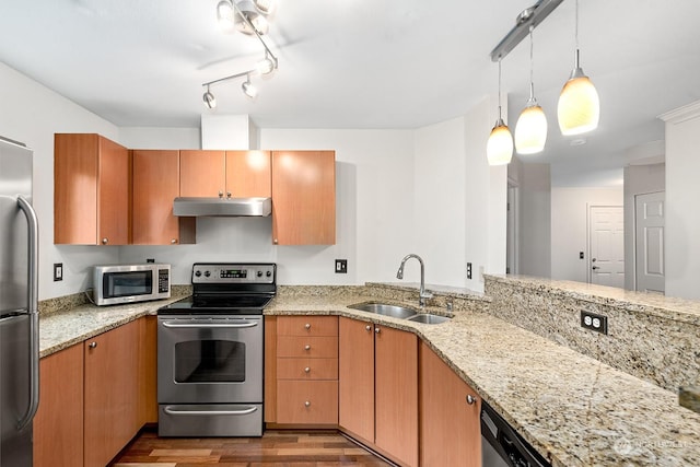 kitchen with wood-type flooring, sink, light stone countertops, kitchen peninsula, and stainless steel appliances