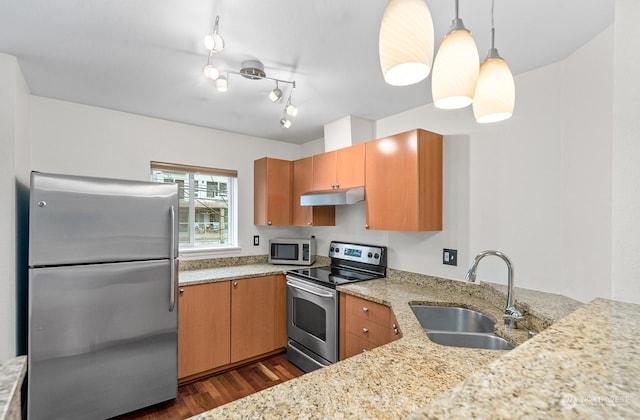 kitchen featuring sink, hanging light fixtures, stainless steel appliances, light stone counters, and dark hardwood / wood-style flooring