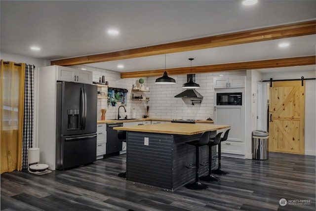 kitchen with pendant lighting, backsplash, black appliances, white cabinets, and a barn door