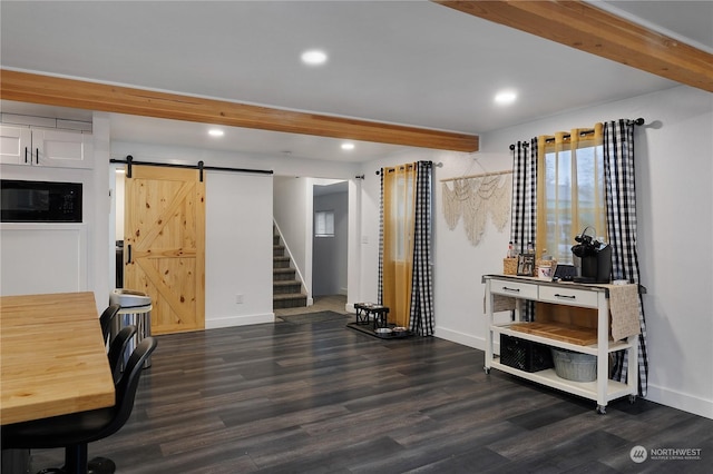 home office with a barn door and dark wood-type flooring