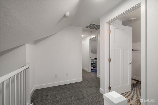 additional living space with a textured ceiling, dark carpet, and lofted ceiling