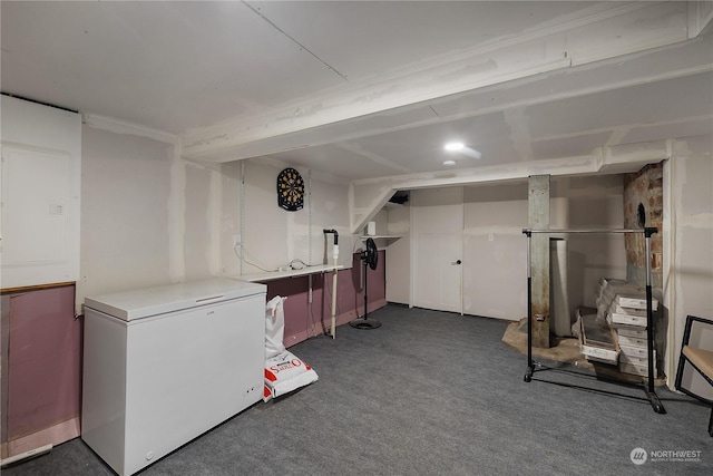 basement featuring dark colored carpet and refrigerator