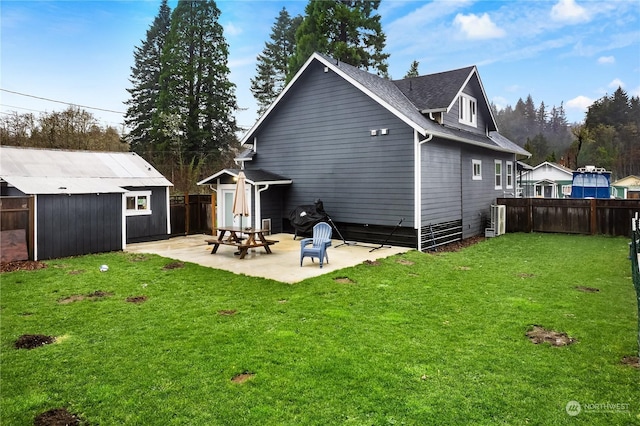 back of property with a yard, a patio, and a storage shed