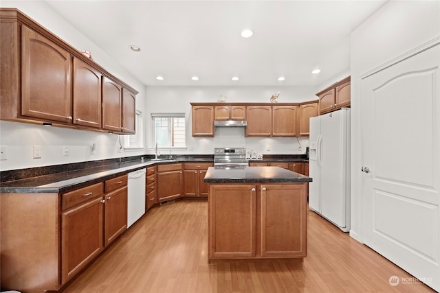 kitchen with a center island, light wood-style floors, a sink, white appliances, and under cabinet range hood