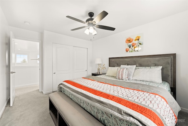 bedroom with a ceiling fan, baseboards, a closet, and light colored carpet