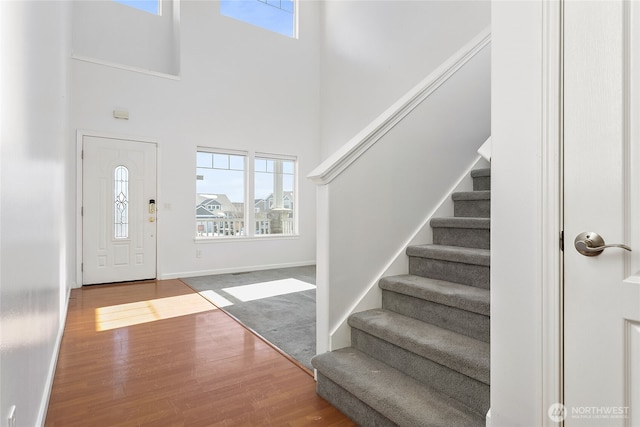 foyer entrance featuring a towering ceiling, a wealth of natural light, and wood-type flooring