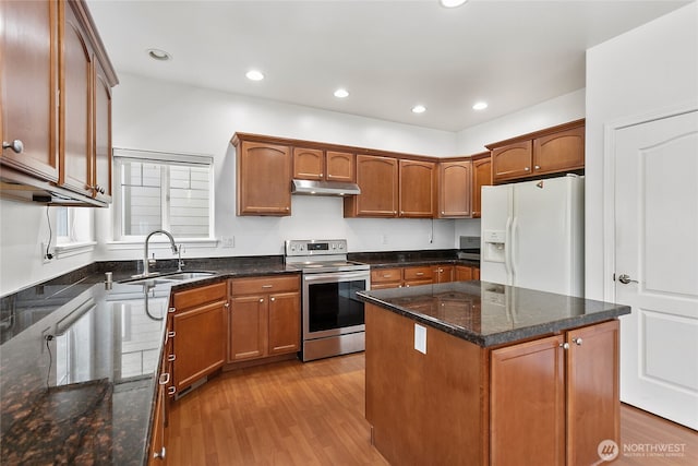 kitchen with under cabinet range hood, white refrigerator with ice dispenser, a sink, light wood-style floors, and stainless steel range with electric stovetop