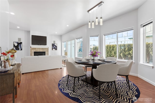 dining room with baseboards, a fireplace, wood finished floors, and recessed lighting