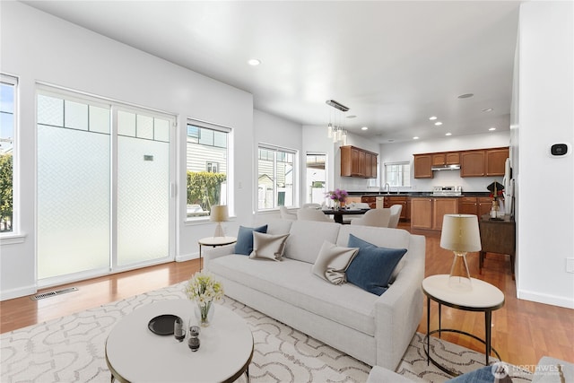 living room featuring light wood-style floors, recessed lighting, visible vents, and baseboards