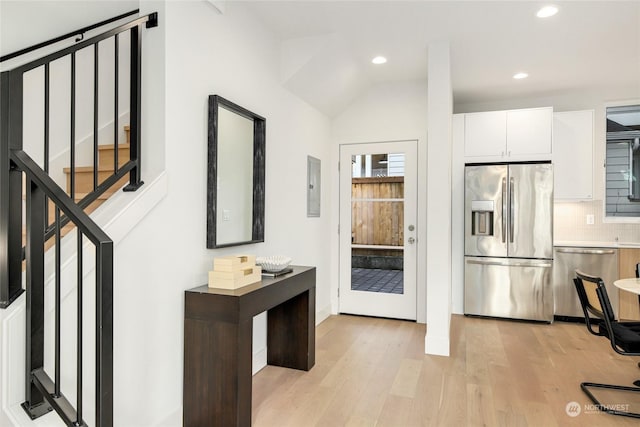 kitchen featuring white cabinetry, stainless steel appliances, tasteful backsplash, electric panel, and light hardwood / wood-style floors