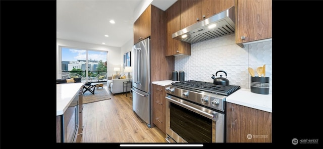 kitchen featuring light hardwood / wood-style floors, exhaust hood, premium appliances, and tasteful backsplash