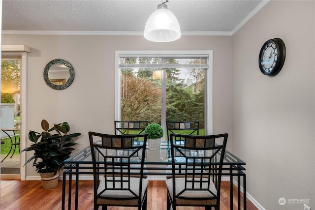 dining room with a textured ceiling, ornamental molding, and wood-type flooring