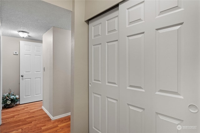 corridor featuring a textured ceiling and light hardwood / wood-style flooring