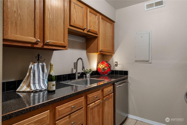 kitchen with light tile patterned floors, dark stone countertops, dishwasher, electric panel, and sink