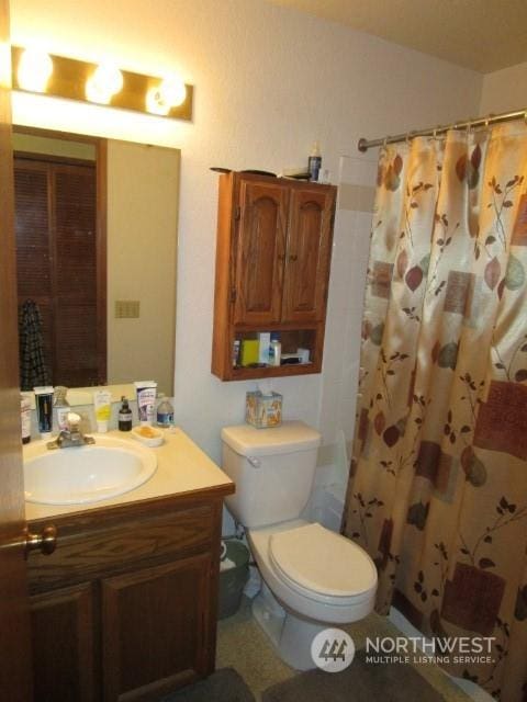 bathroom featuring a shower with shower curtain, vanity, and toilet