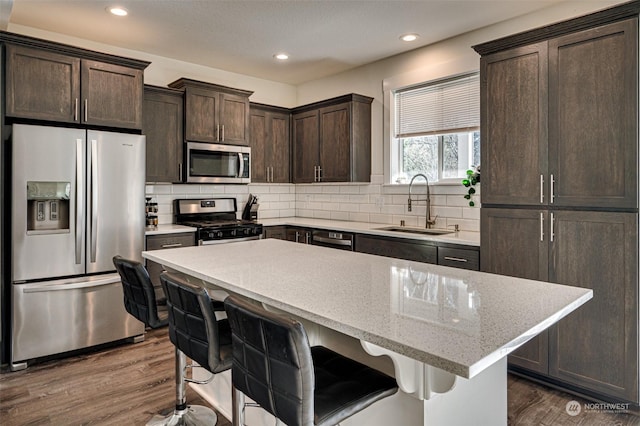 kitchen with sink, a center island, dark wood-type flooring, backsplash, and appliances with stainless steel finishes