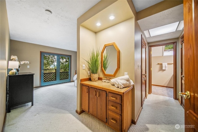 corridor featuring a skylight, light colored carpet, and plenty of natural light