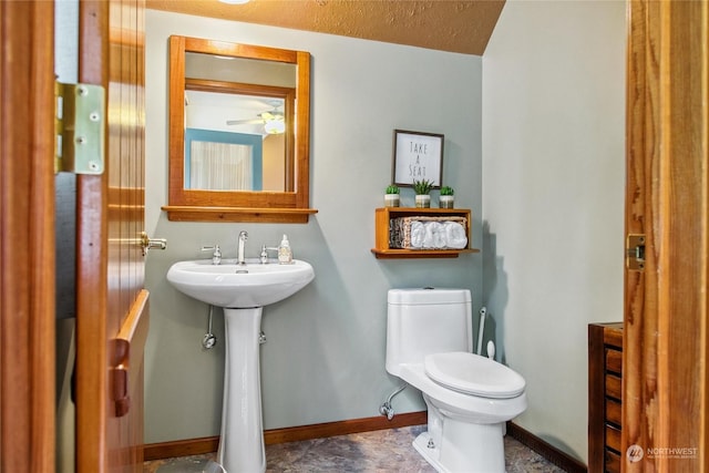 bathroom with a textured ceiling, toilet, ceiling fan, and sink