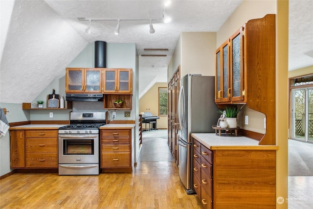 kitchen with a textured ceiling, light wood-type flooring, stainless steel appliances, and extractor fan