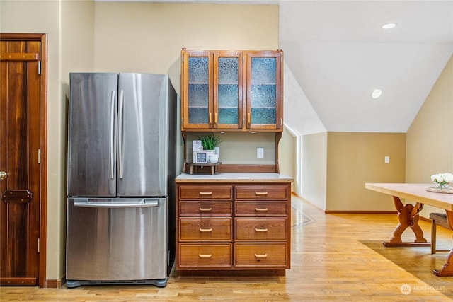 kitchen with light hardwood / wood-style flooring, stainless steel refrigerator, and lofted ceiling