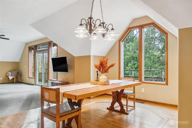 carpeted dining room with a chandelier and vaulted ceiling