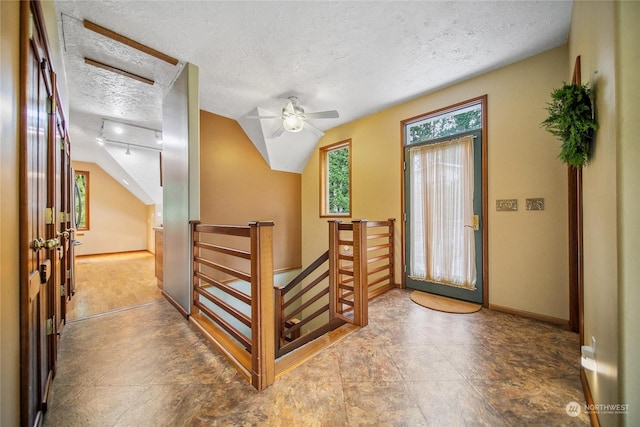 entryway featuring track lighting, ceiling fan, a textured ceiling, and vaulted ceiling