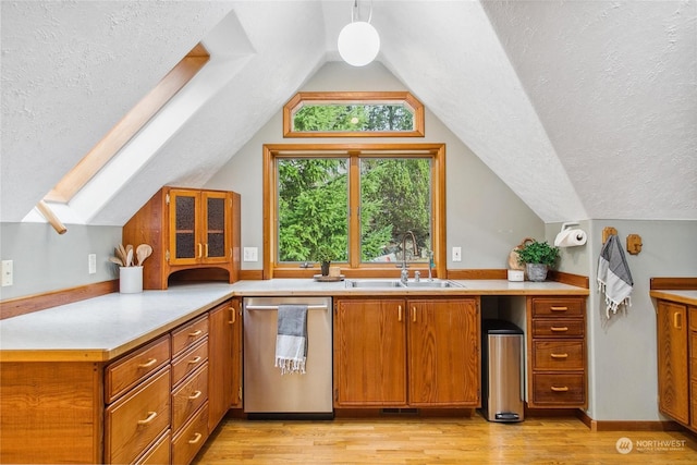 kitchen with light wood-type flooring, stainless steel dishwasher, a textured ceiling, lofted ceiling with skylight, and sink