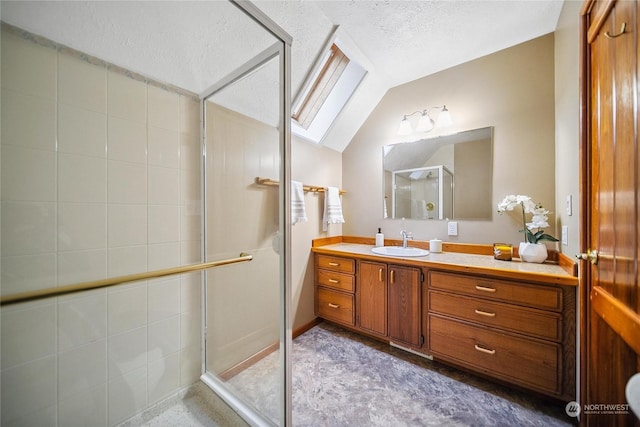 bathroom featuring a textured ceiling, vanity, a shower with shower door, and vaulted ceiling with skylight