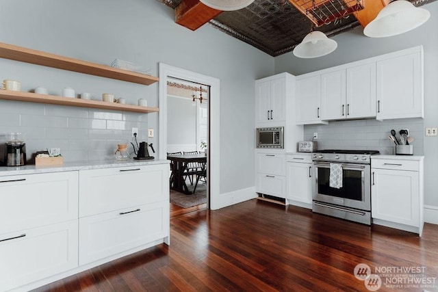 kitchen with appliances with stainless steel finishes, brick ceiling, white cabinetry, and tasteful backsplash