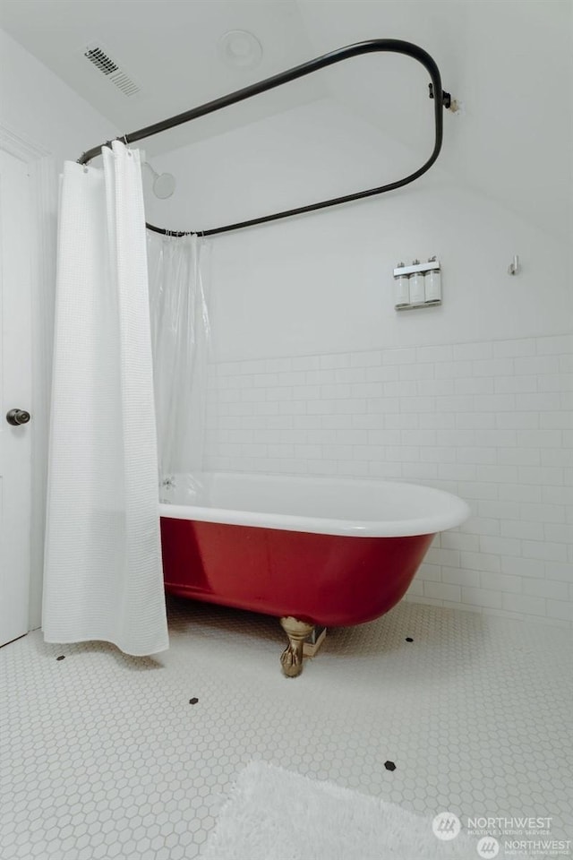 bathroom with tile walls, tile patterned flooring, and shower / bath combination with curtain