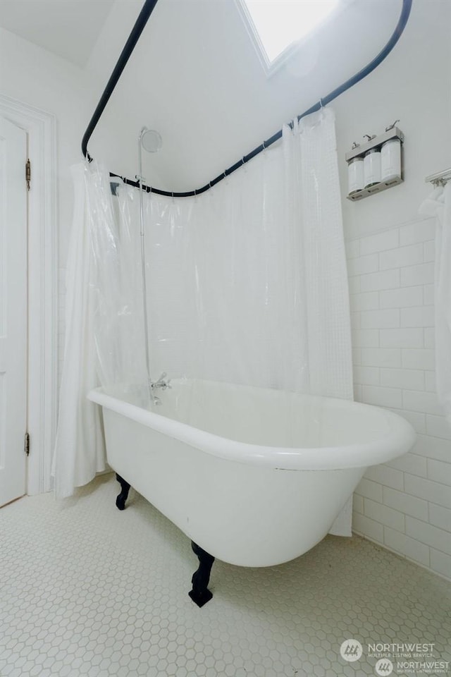 bathroom featuring tile patterned flooring, tile walls, and a bath