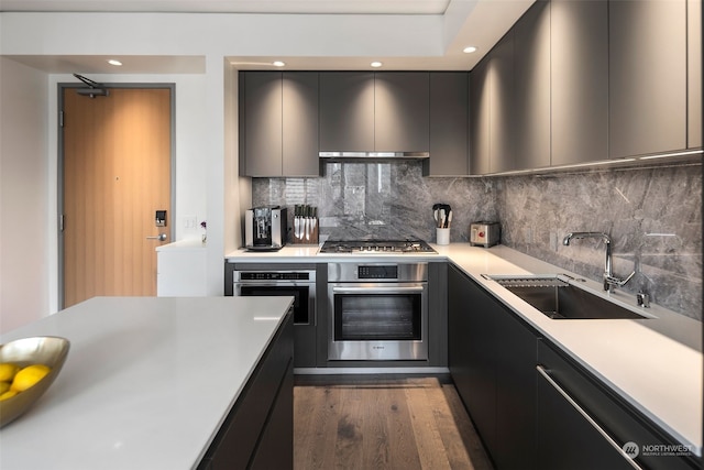 kitchen with decorative backsplash, appliances with stainless steel finishes, dark hardwood / wood-style flooring, extractor fan, and sink