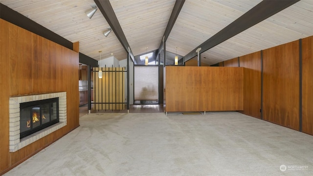 unfurnished living room featuring light carpet, beam ceiling, wooden ceiling, a fireplace, and wood walls