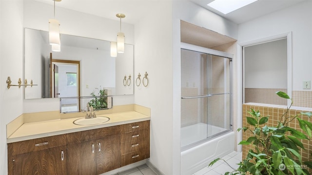 bathroom featuring tile patterned floors, vanity, bath / shower combo with glass door, and a skylight